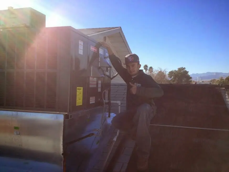 HVAC technician performing Heat Pump Repair on a rooftop unit in Ken Caryl